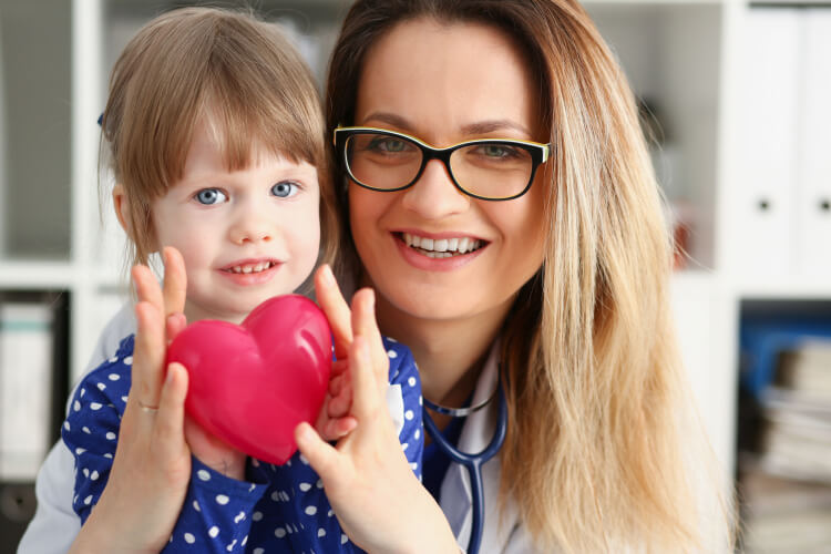 physician with young girl holding heart 