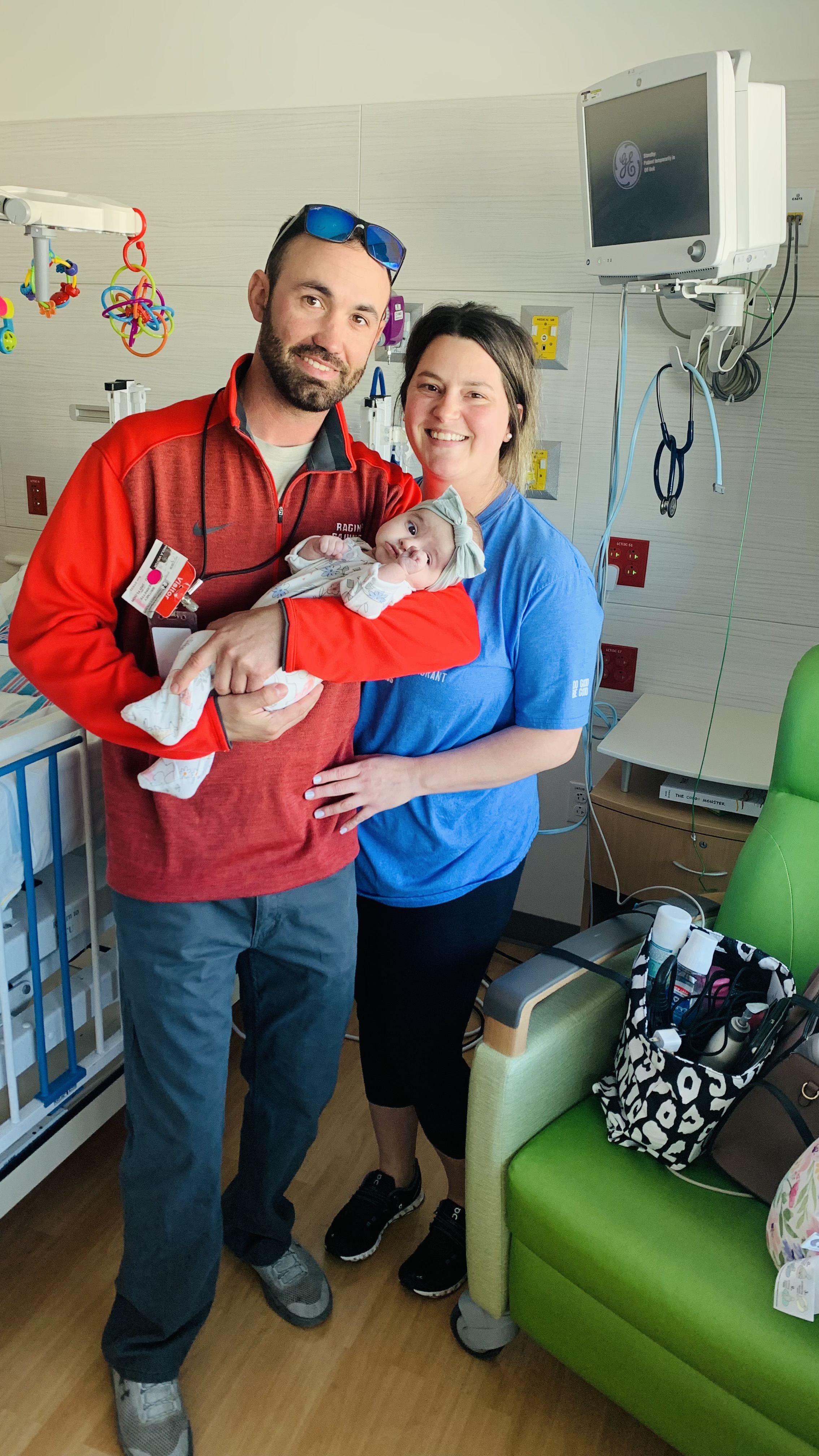 parents holding their child in hospital room 