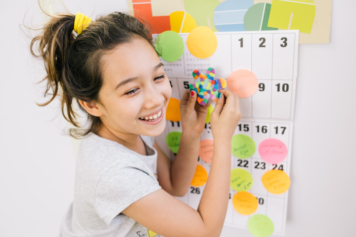 young girl standing next to wall calendar