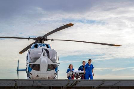 Three physicians escort a patient from a medical helicoptor