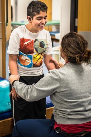 Therapist working with a smiling boy in physical rehabilitation