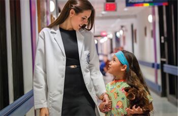 Smiling female physician looking down at a female pediatric patient