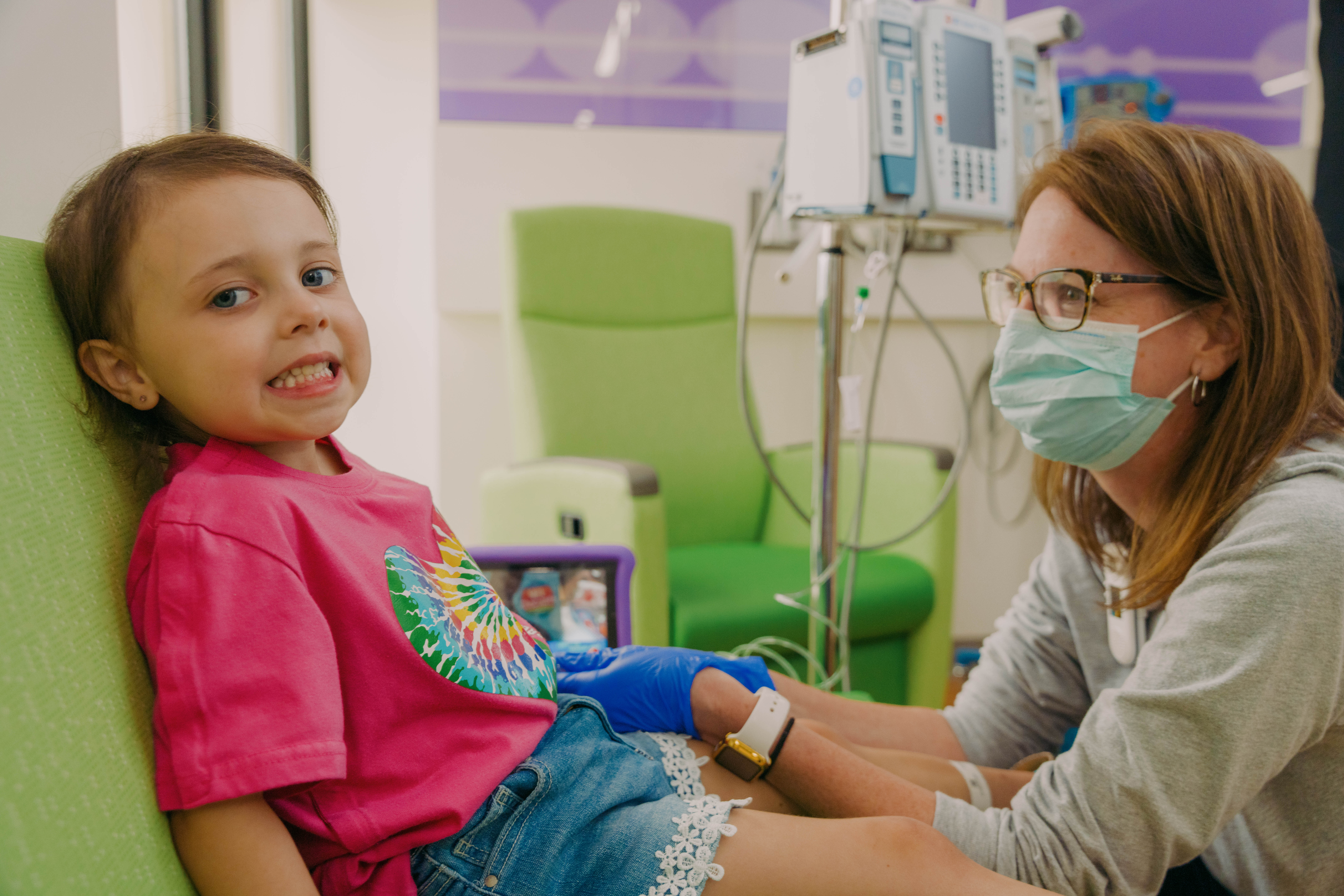 child smiling with provider as child is connected to a machine in hospital