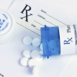 close up image of a prescription bottle spilled out on top of an RX pad of paper.